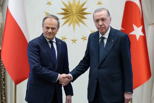 الرئيس التركي رجب طيب إردوغان ورئيس الوزراء البولندي دونالد توسك يتصافحان خلال لقائهما بالقصر الرئاسي في أنقرة يوم 12 مارس 2025 (إ.ب.أ)