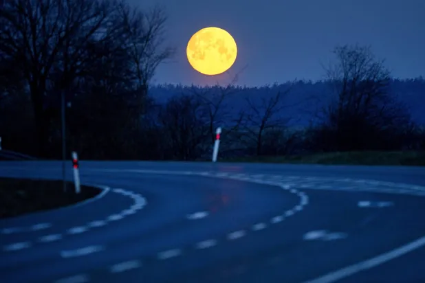 يغرب القمر خلف طريق في ويرهايم بالقرب من فرانكفورت (أ.ب)
