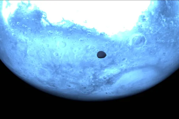 يظهر المريخ باللون الأزرق الفاتح في الصورة ويظهر ديموس كنقطة داكنة أسفل الصورة (أ.ف.ب)