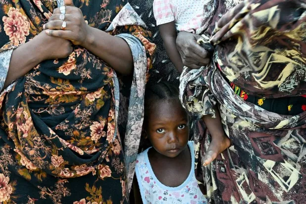 A child stands between two women at a school turned into a shelter, in Port Sudan, Sudan, August 29, 2024. (Reuters)