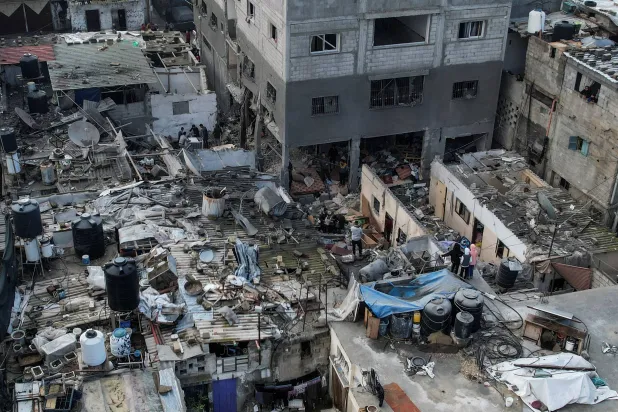 فلسطينيون يتجمعون في موقع غارة إسرائيلية على منزل (رويترز)