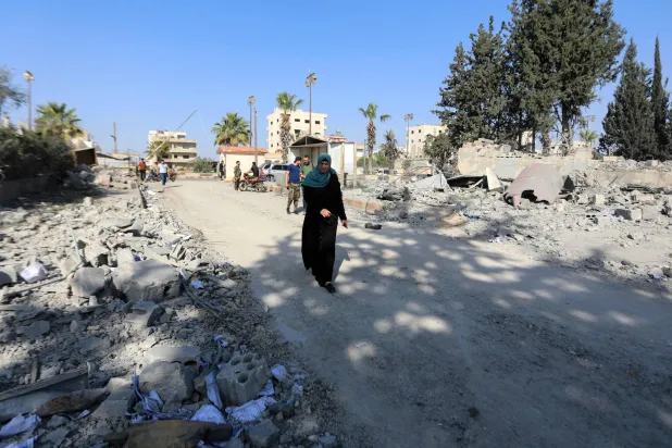 A woman walks amid debris after an Israeli strike a day earlier in Syria's southern town of Daraa, on March 18, 2025. (Photo by Bakr ALKASEM / AFP)