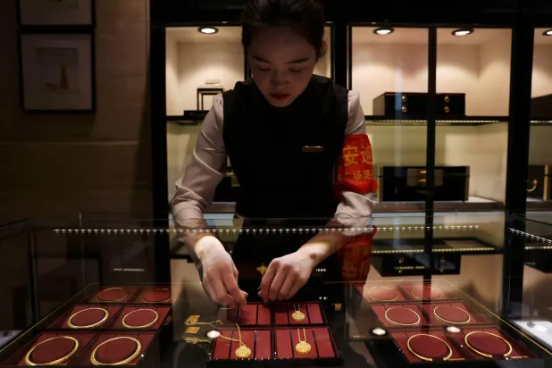 موظفة ترتب القلائد الذهبية في خزانة عرض في متجر للمجوهرات في بكين (رويترز)