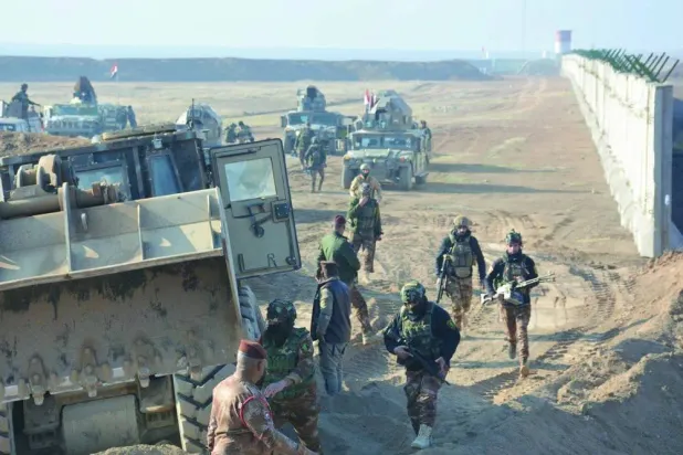 Iraqi soldiers deployed along a concrete barrier stretching across parts of the border with Syria. (Security media)