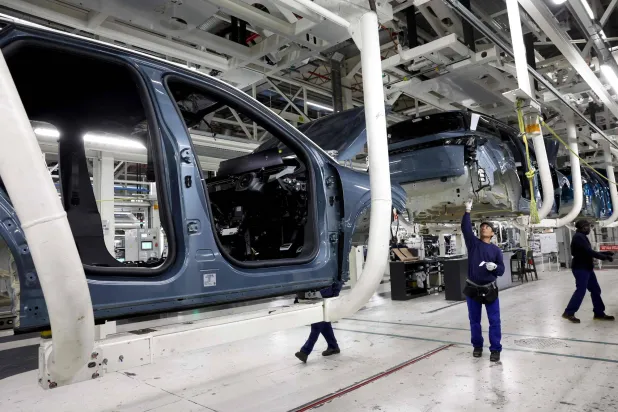 موظفون يعملون على خط إنتاج سيارة كهربائية في مصنع ستيلانتس بسوشو شرق فرنسا (أ.ف.ب)