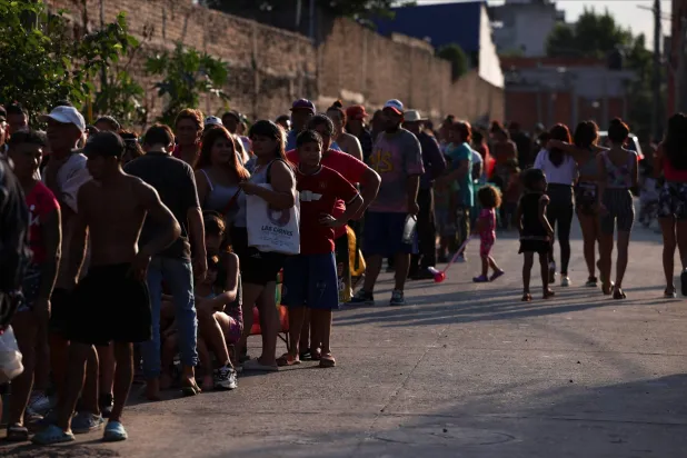 طابور طويل ينتظر مصطفوه إعانات غذائية في أحد الأحياء الفقيرة بالأرجنتين (رويترز)