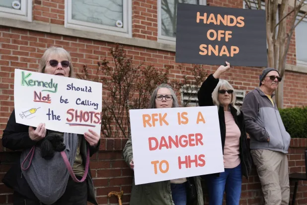 موظفون يتظاهرون خارج مدرسة سانت جوزيف في مارتينسبورغ بفيرجينيا الغربية ضد إجراءات التسريح التي تمارسها وزارة الصحة (أ.ب)