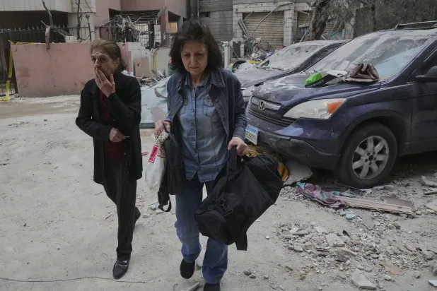 امرأتان تغادران مسكنهما القريب من موقع استهداف إسرائيلي للضاحية الجنوبية لبيروت (أ.ب)