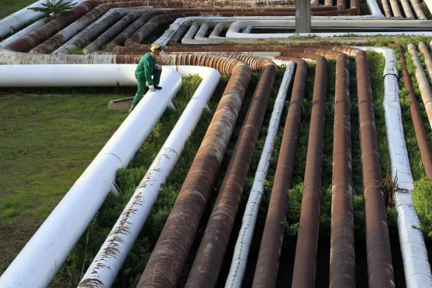 موظف يمشي فوق خطوط أنابيب في مصفاة دونا التابعة لمجموعة النفط والغاز المجرية (رويترز)