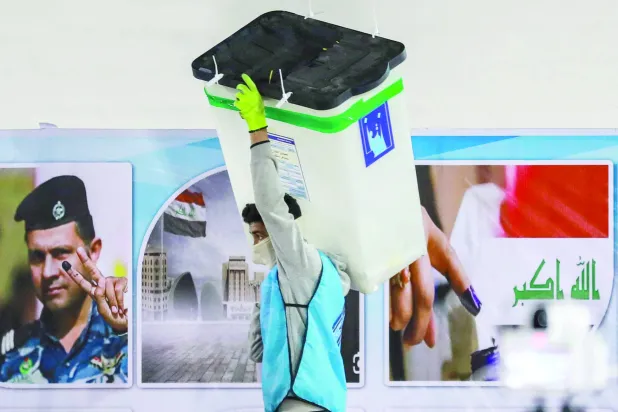 موظف في مفوضية الانتخابات العراقية يحمل صندوقاً لفرز الأصوات في ديسمبر 2023 (أ.ف.ب)