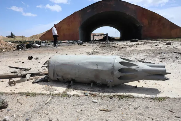  İsrail'in Suriye'nin orta kesimindeki Hama askeri havaalanına düzenlediği hava saldırısının ardından hangarın dışında yıkımı inceleyen bir adam (AFP)