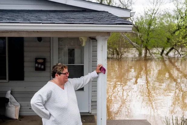 مواطنة أميركية تنظر إلى نهر ليكينغ وهو يرتفع ويبدأ في إغراق قبو منزلها في فالموث بولاية كنتاكي (أ.ف.ب)