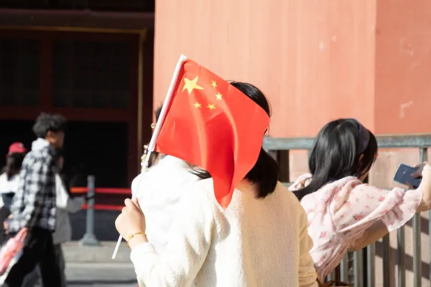 شخص يحمل العلم الصيني في بكين (إ.ب.أ)