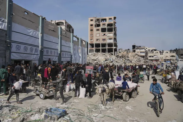 فلسطينيون يتسلمون أكياس الدقيق وغيرها من المساعدات الإنسانية التي توزعها «الأونروا» في جباليا بقطاع غزة (أ.ب)