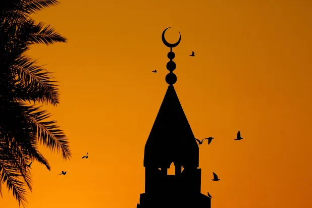 طيور تحلّق حول مئذنة مسجد في العاصمة القطرية الدوحة فجر يوم عيد الفطر(أ.ف.ب)