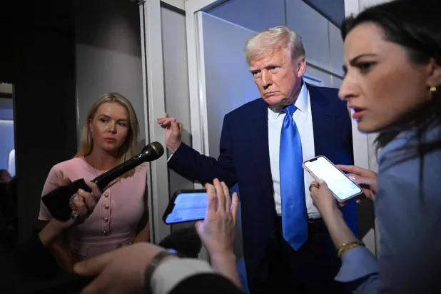 الرئيس الأميركي دونالد ترمب وخلفه المتحدثة باسم البيت الأبيض كارولين ليفيت خلال تصريحات للصحافيين على متن الطائرة الرئاسية «إير فورس وان» (أ.ف.ب)