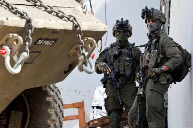 Two Israeli soldiers stand next to a military vehicle during an operation in Jenin, West Bank, March 4, 2025 (Reuters). 