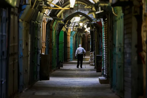 رجل يمر أمام متاجر مغلقة خلال إضراب عام احتجاجاً على القصف الإسرائيلي على غزة في البلدة القديمة بالقدس (رويترز)