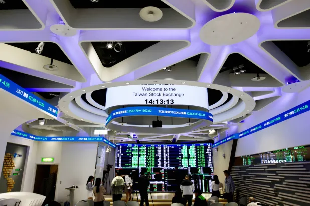 أشخاص يراقبون قيم الأسهم داخل مكتب بورصة تايوان في تايبيه (إ.ب.أ)