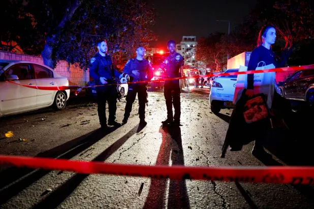 عناصر من فرق الطوارئ الإسرائيلية في موقع سقوط صاروخ أطلق من غزة باتجاه مدينة عسقلان يوم الأحد (رويترز)