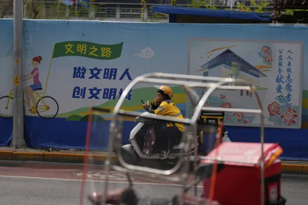 رجل توصيل ينتظر على دراجته في منطقة الشارع المالي في بكين (أ.ب)