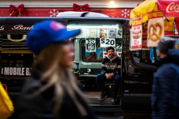 حلاق ينتظر الزبائن داخل شاحنته بشارع داخلي في نيويورك (رويترز)