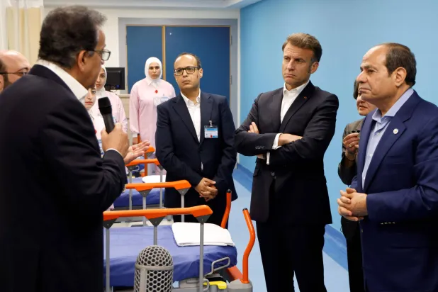 الرئيس المصري عبد الفتاح السيسي والرئيس الفرنسي إيمانويل ماكرون يستمعان إلى الطاقم الطبي في جناح للمرضى الفلسطينيين في مستشفى العريش بمدينة العريش شمال شرق مصر قرب الحدود مع قطاع غزة، 8 أبريل 2025 (أ.ف.ب)