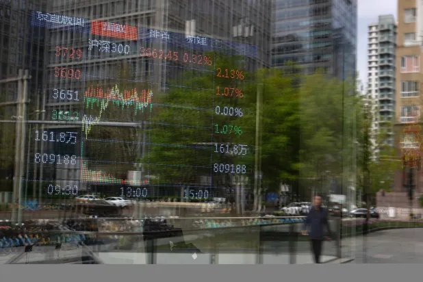 أحد المشاة يمر أمام شاشة عرض مؤشر «سي إس آي 300» في بكين (إ.ب.أ)