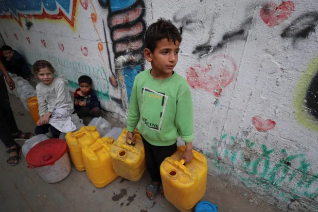 طفل يحمل عبوتين لملئهما بالماء في مدينة غزة في 6 أبريل 2025 (رويترز)