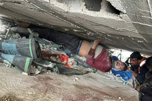 İsrail’in dün Gazze'nin doğusundaki Şucaiyye Mahallesi'ne düzenlediği saldırı sonucu yıkılan bir binanın enkazı altında kalan bir Filistinli (Reuters)