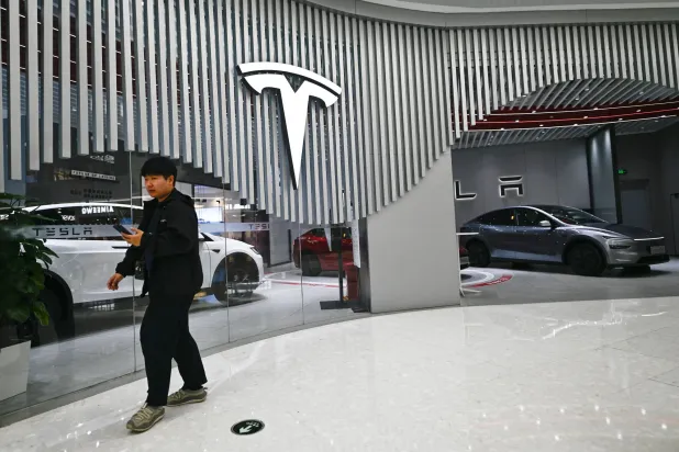 رجل يسير خارج معرض لشركة «تسلا» في العاصمة الصينية بكين (أ.ف.ب)