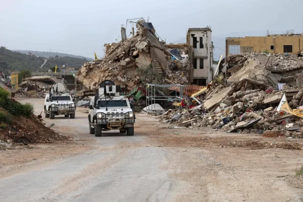 آليات تابعة لقوات حفظ السلام التابعة للأمم المتحدة تسير أمام مبانٍ مدمرة أثناء قيامها بدورية في قرية كفركلا جنوب لبنان بالقرب من الحدود مع إسرائيل (أ.ف.ب)