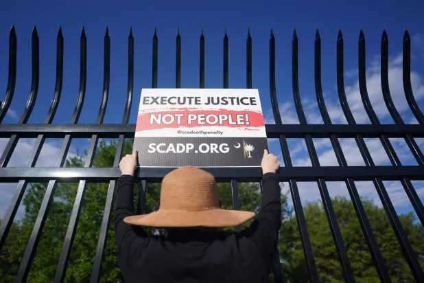 متظاهرة تحمل لافتةً ضد عقوبة الإعدام خارج إدارة الإصلاحيات قبل إعدام السجين ميكال مهدي رمياً بالرصاص في ولاية كارولينا الجنوبية (أ.ف.ب)