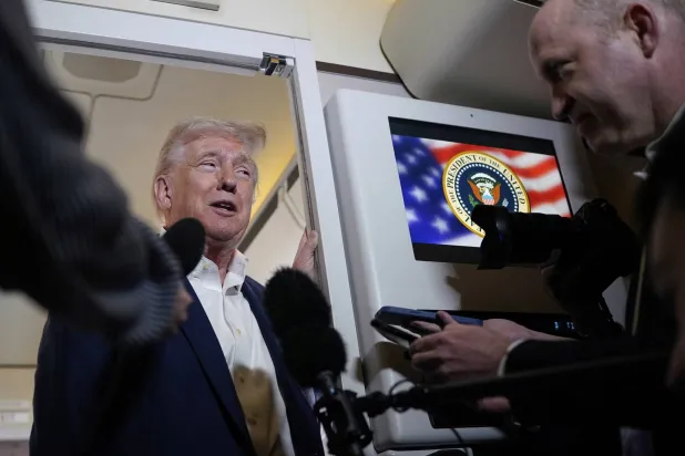 ترمب يتحدث للصحافيين على متن «إير فورس وان» أثناء توجهه إلى مطار بالم بيتش الدولي فلوريدا أمس (أ.ب)