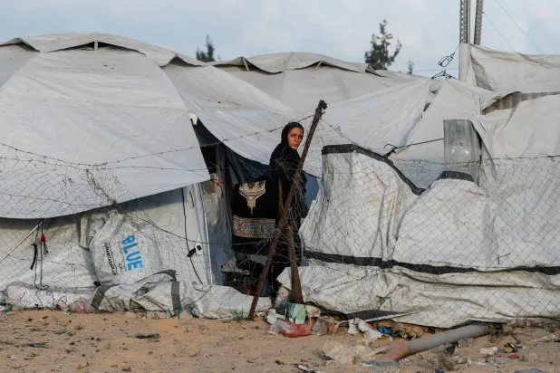 فلسطينية تقف بين خيام النازحين في خان يونس جنوب قطاع غزة (رويترز)