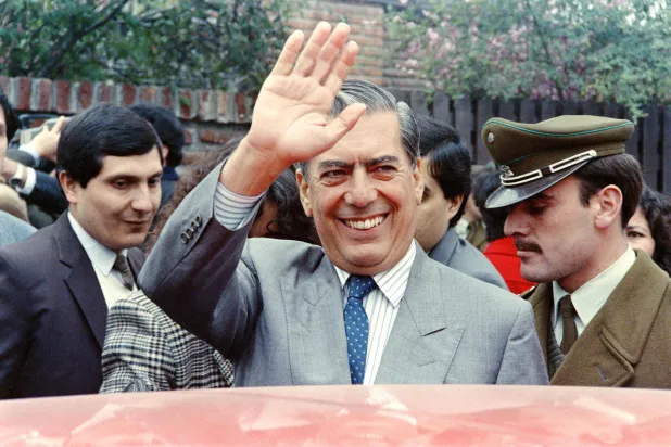 الكاتب البيروفي والمرشح الرئاسي عن الجبهة الديمقراطية البيروفية آنذاك ماريو فارغاس يوسا يلوّح لأنصاره بعد مؤتمر صحافي أشاد فيه بسياسة السوق المفتوحة التي انتهجتها الحكومة العسكرية التشيلية 19 أغسطس 1989 (أ.ف.ب)