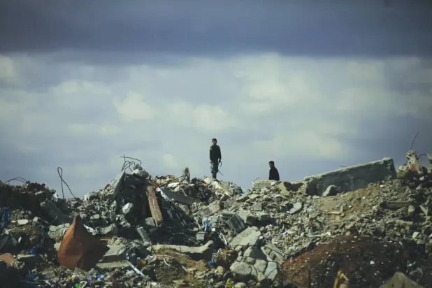 Yerinden edilmiş Filistinliler dün Gazze'nin merkezindeki Bureyc kampındaki çöken binaların enkazı üzerinde (DPA)