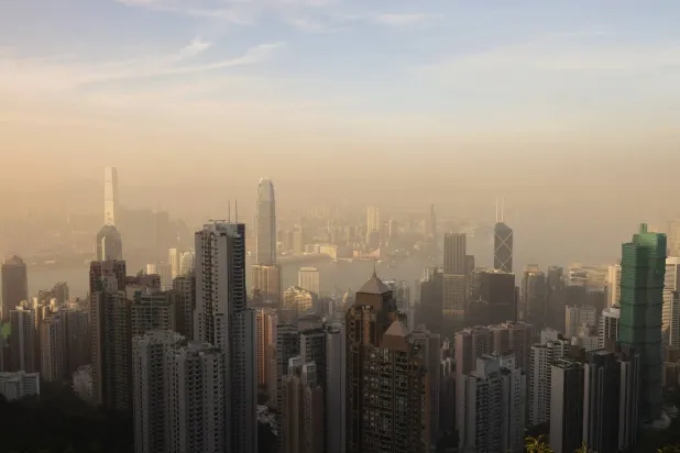 ميناء فيكتوريا ومنطقة الأعمال المركزية في حالة من الضباب مع غروب الشمس فوق هونغ كونغ (رويترز) 