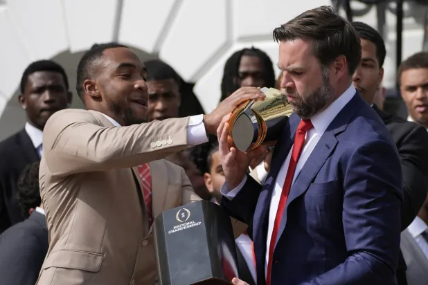 لحظة سقوط الكأس من يد نائب الرئيس الأميركي جيه دي فانس وبجانبه لاعب كرة القدم بجامعة ولاية أوهايو تريفيون هندرسون (أ.ب)