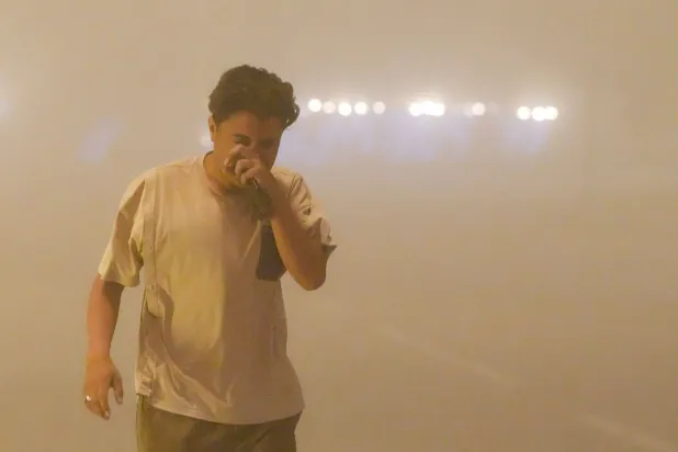 يكافح أحد المشاة لالتقاط أنفاسه أثناء سيره على جانب الطريق في ظل ظروف الرؤية المنخفضة بسبب عاصفة غبارية هائلة في مدينة النجف (أ.ف.ب)