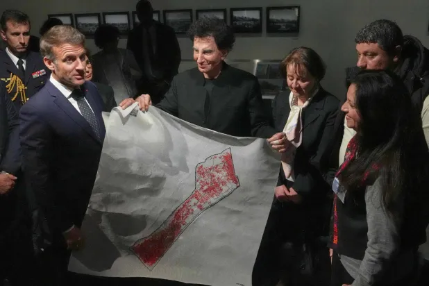 ماكرون خلال زيارته معرض «كنوز غزة» في معهد العالم العربي يوم الاثنين ويظهر ممسكاً بخريطة «فلسطين» مرسومة على قماش (أ.ف.ب)