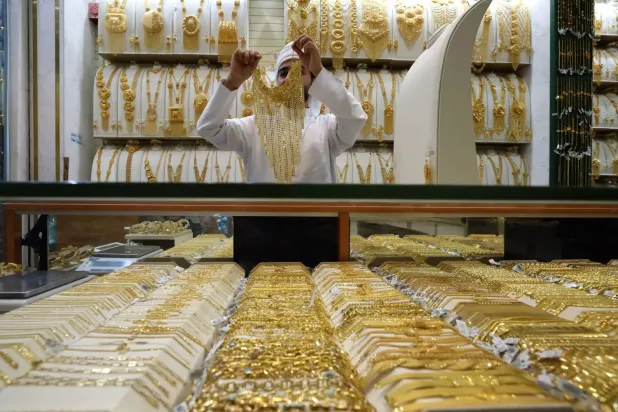 Dubai'deki Altın Çarşısı'nda bulunan bir kuyumcu dükkanında müşteriye altın bir parça gösteriliyor. (EPA)