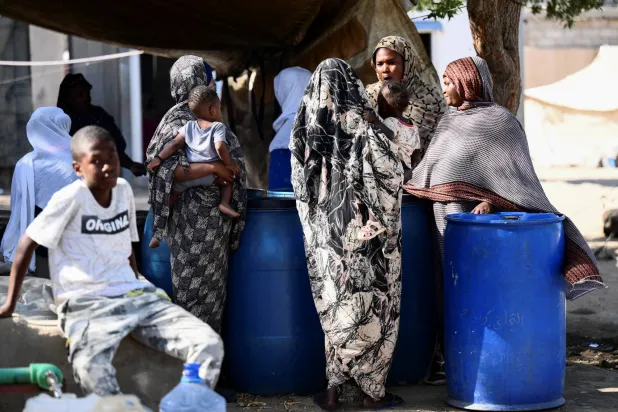 سودانيات نازحات يتحدثن بجوار خيامهن في مخيم «عبد الله ناجي» للإيواء في بورتسودان الذي يأوي نازحين معظمهم من العاصمة الخرطوم (رويترز)