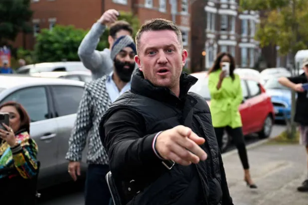 ستيفن ياكسلي لينون المعروف باسم تومي روبنسون يلوّح بيده قبل وصوله إلى مركز شرطة فولكستون ببريطانيا 25 أكتوبر 2024 (رويترز)