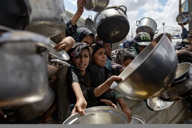 نازحون يتدافعون بأوعيتهم الخاوية للحصول على حصة من طعام من «تكية خيرية» في خان يونس بجنوب قطاع غزة في 11 أبريل 2025 (إ.ب.أ)