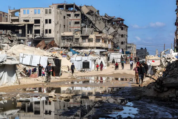 فلسطينيون يسيرون بجوار خيام أُقيمت بالقرب من أنقاض مبنى منهار في حي النصر غرب مدينة غزة 15 أبريل 2025 (أ.ف.ب)