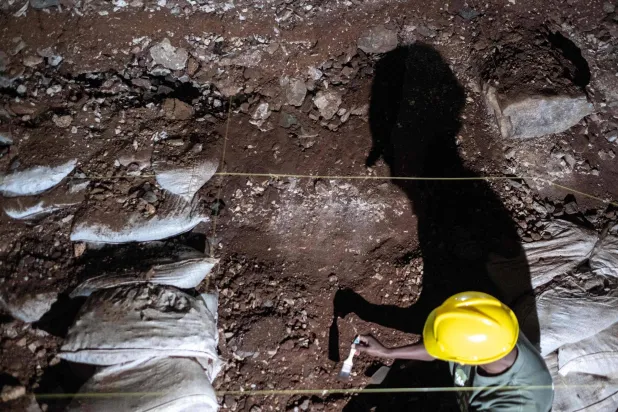 فني الحفريات يبحث في الرواسب عن بقايا هياكل عظمية في الكهوف (أ.ف.ب)