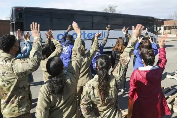 في هذه الصورة التي قدمتها وزارة الأمن الداخلي، يلوح عسكريون وموظفون من وزارة الأمن الداخلي وأفراد من غير الحكوميين بينما تغادر الحافلة الأخيرة التي تحمل لاجئين أفغاناً قاعدة ماكجواير ديكس ليكهورست المشتركة في نيوجيرسي في 19 فبراير 2022 (أ.ب)