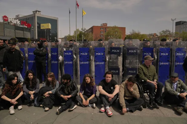 طلاب جامعات يجلسون أمام حواجز الشرطة أثناء محاكمة زملائهم (أ.ب)