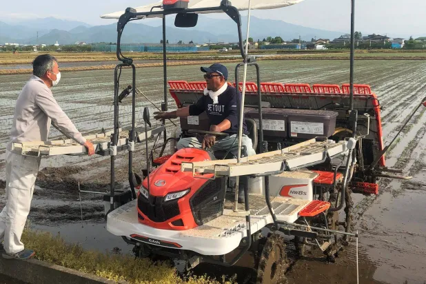 مزارع يتحدث مع آخر في حقل أرز بشمال اليابان (رويترز)
